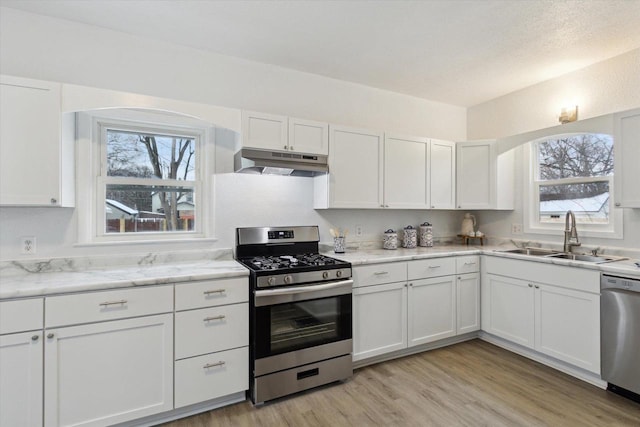 kitchen featuring light stone countertops, appliances with stainless steel finishes, sink, white cabinets, and light hardwood / wood-style floors