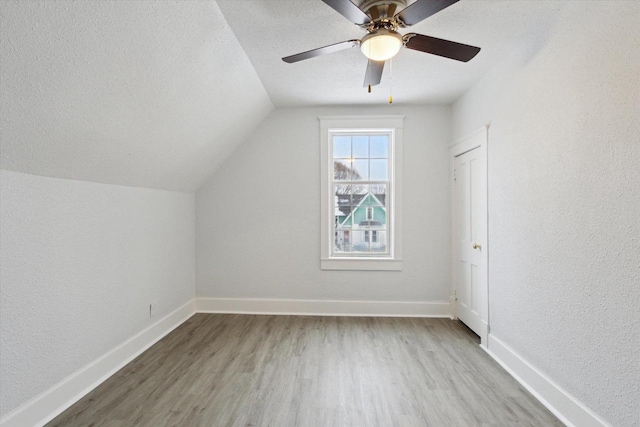 bonus room with a textured ceiling, ceiling fan, lofted ceiling, and light wood-type flooring