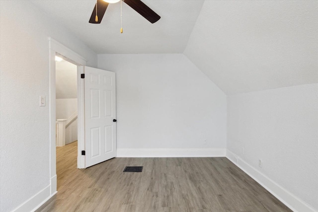 bonus room with wood-type flooring, a textured ceiling, vaulted ceiling, and ceiling fan