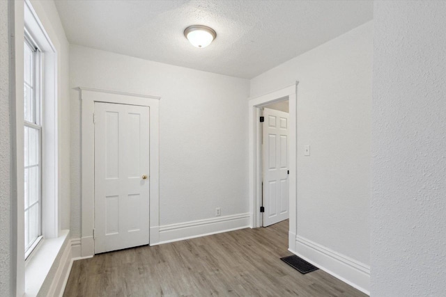 unfurnished room featuring a textured ceiling and light wood-type flooring