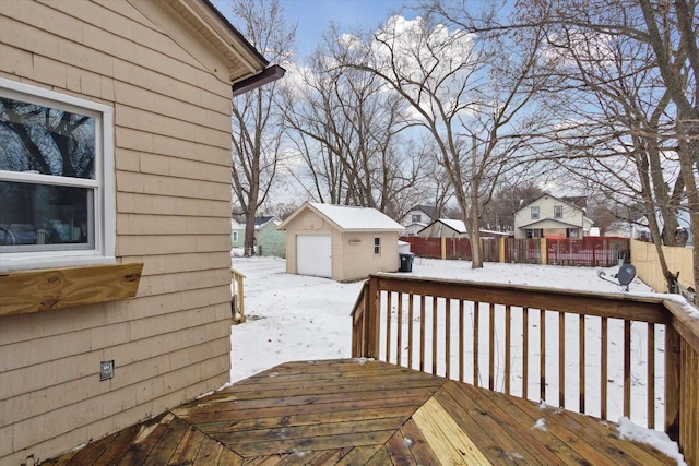 snow covered deck featuring an outdoor structure and a garage