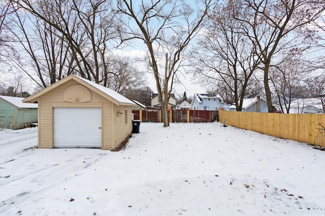 yard layered in snow featuring a garage and an outdoor structure