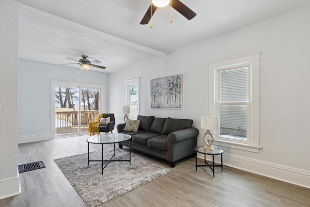 living room with hardwood / wood-style floors, ceiling fan, and beamed ceiling