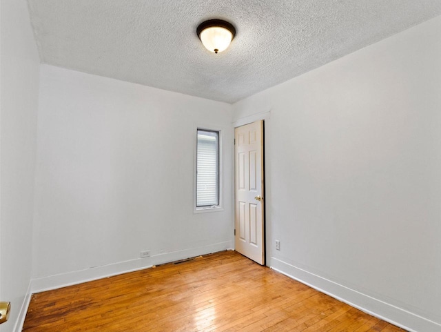 unfurnished room with a textured ceiling and light wood-type flooring