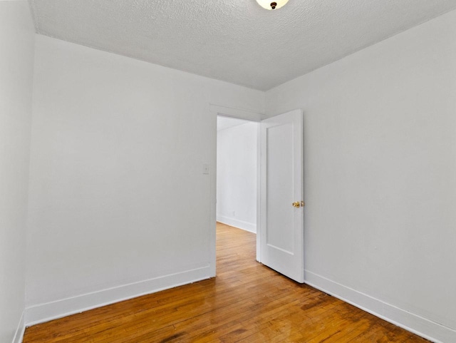 empty room with hardwood / wood-style flooring and a textured ceiling