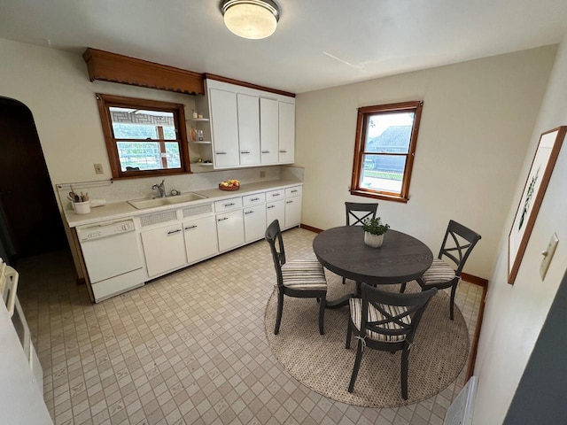 kitchen with white dishwasher, white cabinetry, and sink