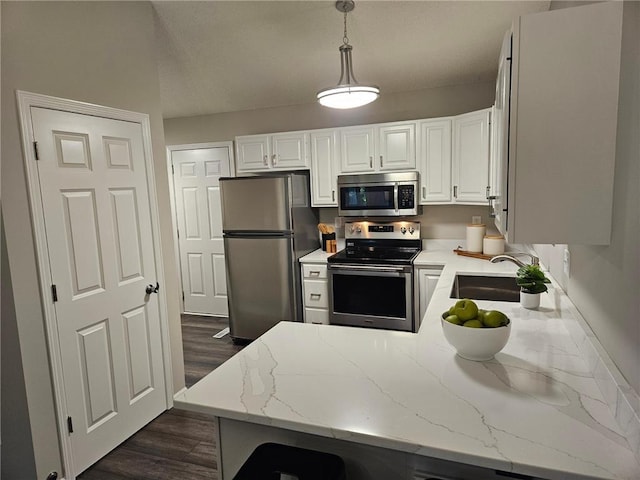 kitchen with sink, hanging light fixtures, light stone counters, white cabinetry, and stainless steel appliances