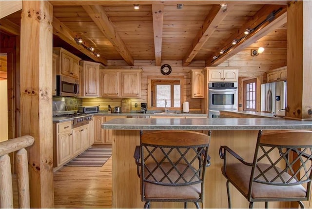 kitchen with a breakfast bar, light brown cabinets, stainless steel appliances, and track lighting