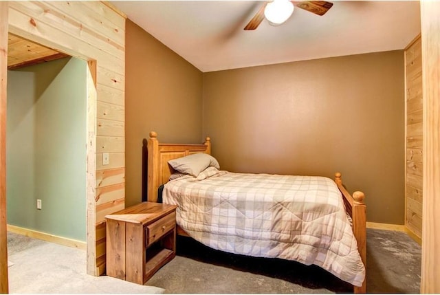 bedroom with ceiling fan, wood walls, and light carpet