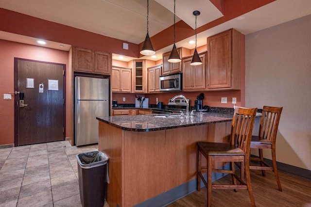 kitchen featuring pendant lighting, kitchen peninsula, sink, and appliances with stainless steel finishes