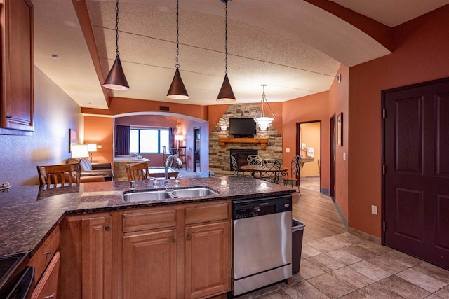 kitchen with dishwasher, a stone fireplace, sink, decorative light fixtures, and range