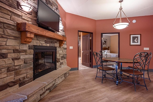 dining space with light wood-type flooring and a stone fireplace