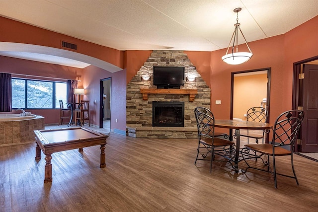 dining area with a fireplace, hardwood / wood-style floors, and pool table