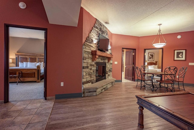 living room featuring wood-type flooring, a textured ceiling, and a stone fireplace