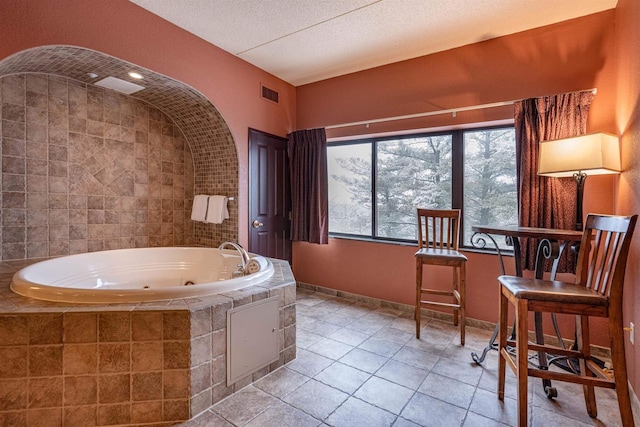 bathroom featuring tile patterned floors, a textured ceiling, and tiled bath