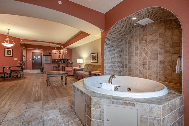 bathroom featuring a relaxing tiled tub and hardwood / wood-style flooring