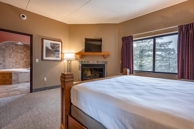 carpeted bedroom with a textured ceiling, a fireplace, and ensuite bath