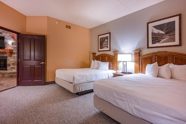 carpeted bedroom featuring a stone fireplace