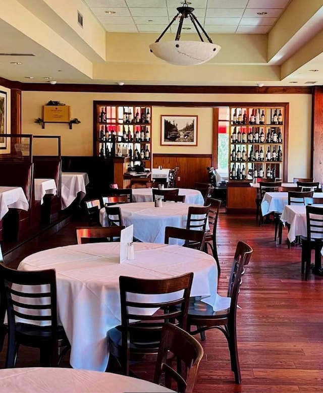 dining area featuring built in shelves, wooden walls, dark wood-type flooring, and indoor bar