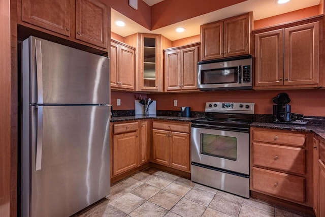 kitchen featuring appliances with stainless steel finishes, dark stone counters, and light tile patterned flooring