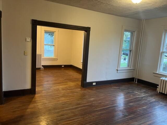 unfurnished room featuring radiator heating unit, dark hardwood / wood-style flooring, and a textured ceiling