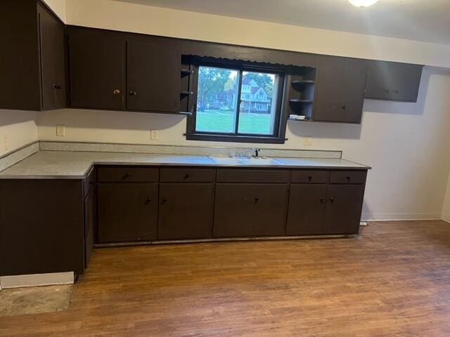 kitchen with sink, dark brown cabinetry, and light hardwood / wood-style flooring