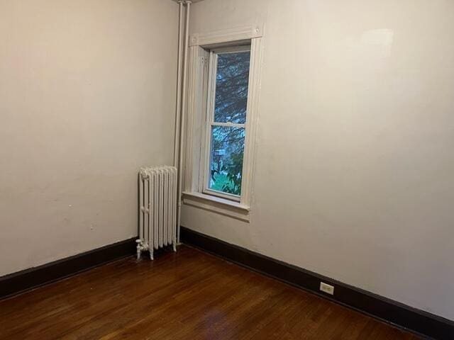 spare room with radiator and dark wood-type flooring