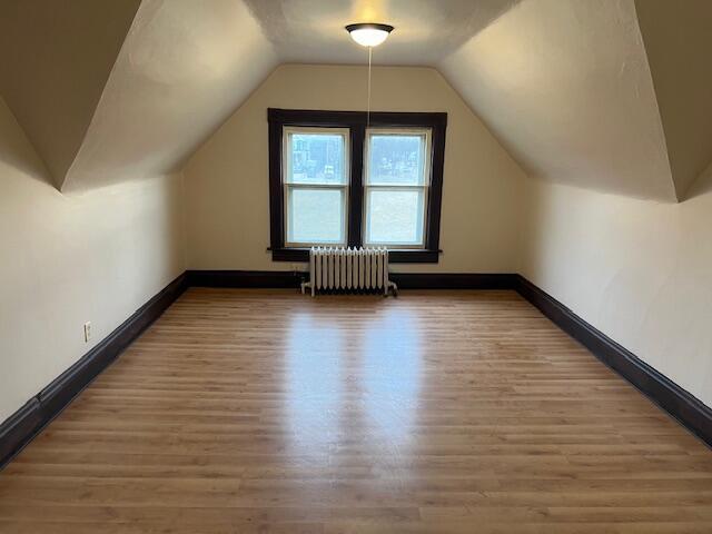 bonus room with radiator heating unit, vaulted ceiling, and wood-type flooring