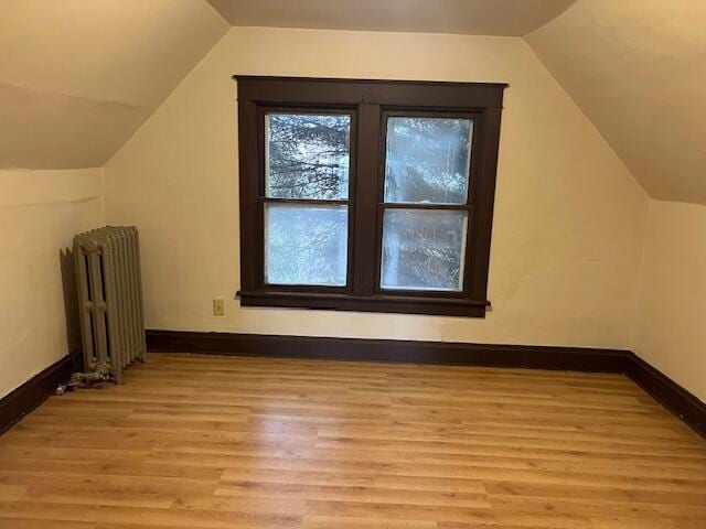 bonus room featuring radiator heating unit, vaulted ceiling, and light hardwood / wood-style flooring