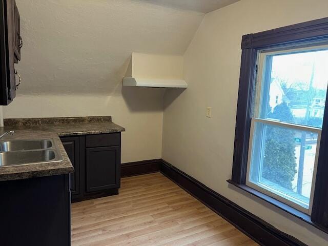 kitchen with vaulted ceiling, sink, and light hardwood / wood-style floors