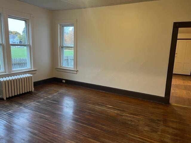 spare room featuring radiator heating unit and dark hardwood / wood-style floors