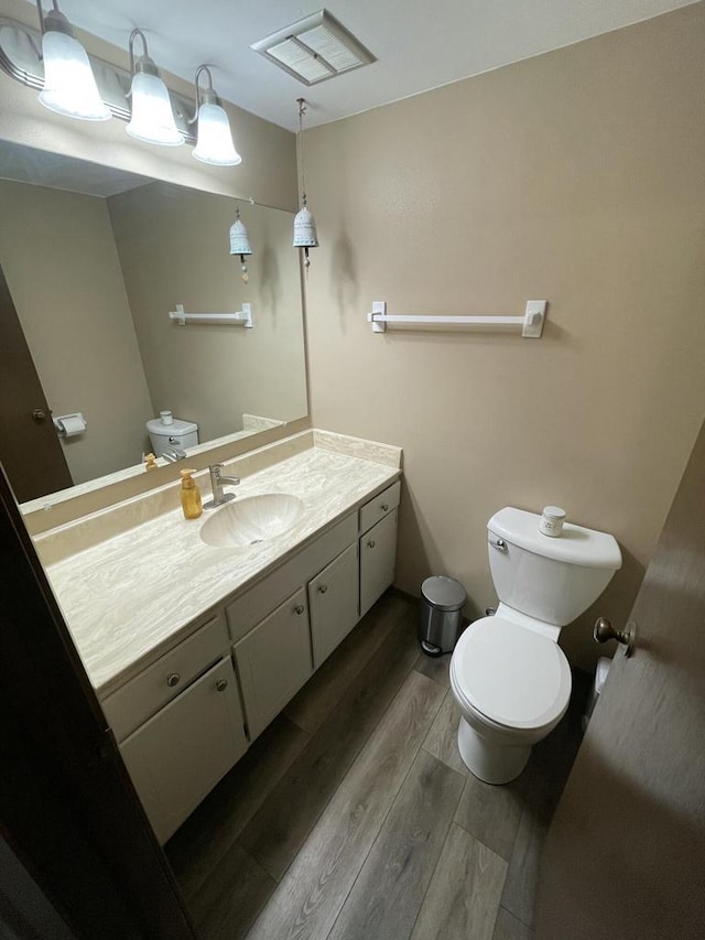 bathroom featuring vanity, wood-type flooring, and toilet