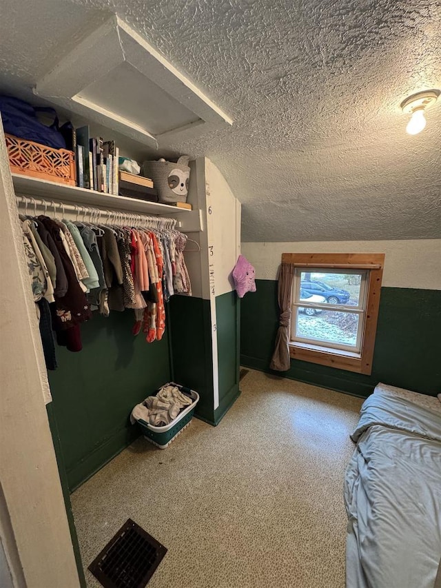 interior space featuring a textured ceiling, carpet floors, and vaulted ceiling