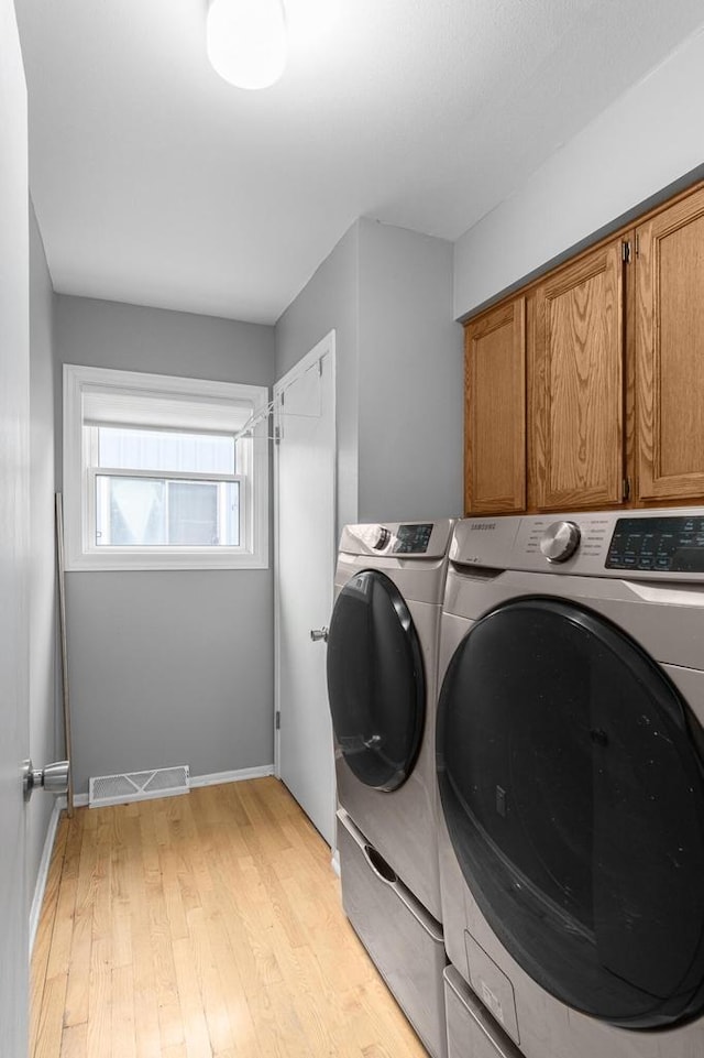 laundry room featuring light hardwood / wood-style floors, cabinets, and separate washer and dryer