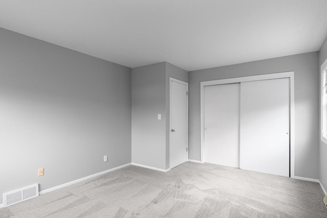 unfurnished bedroom featuring light colored carpet and a closet