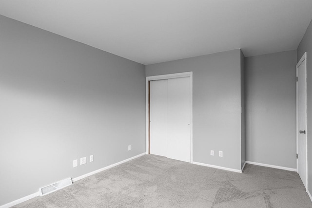 unfurnished bedroom with light carpet and a closet