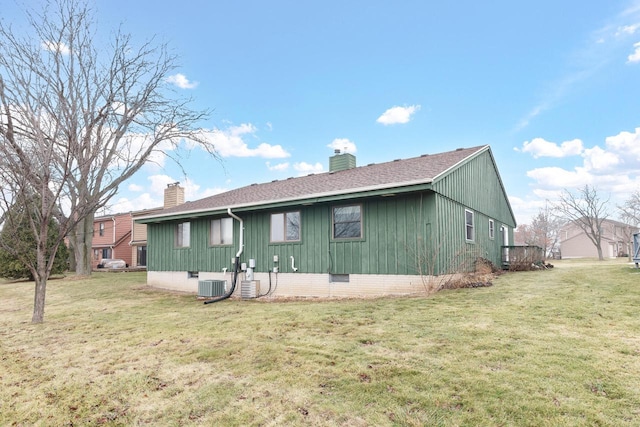 rear view of property with central AC and a lawn