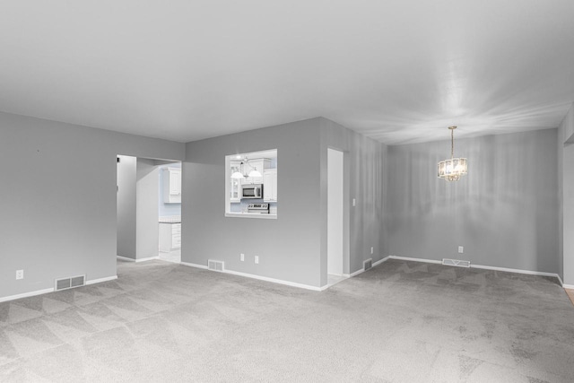 unfurnished living room with a notable chandelier and light colored carpet