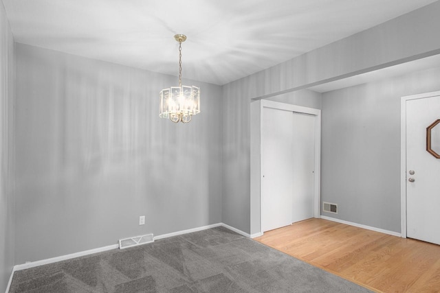 empty room with hardwood / wood-style floors and an inviting chandelier