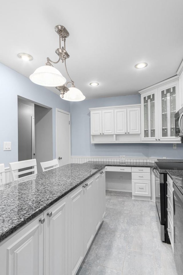 kitchen featuring dark stone countertops, white cabinetry, and pendant lighting