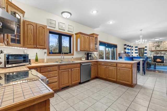 6461 Blue Heron Pointe Dr, Waterford, WI 53185 - kitchen featuring sink, a fireplace, decorative light fixtures, kitchen peninsula, and stainless steel appliances