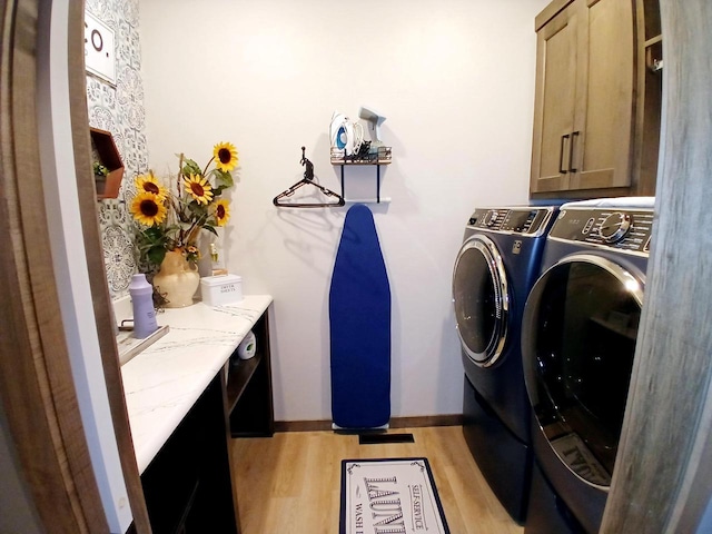 laundry room featuring light hardwood / wood-style floors, cabinets, and washing machine and clothes dryer