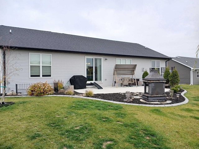 rear view of house with a yard, a patio, and an outdoor fire pit