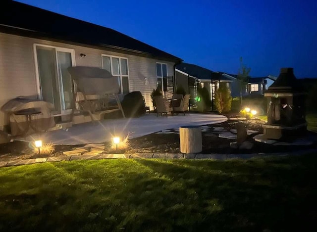 back house at night with a yard and a patio