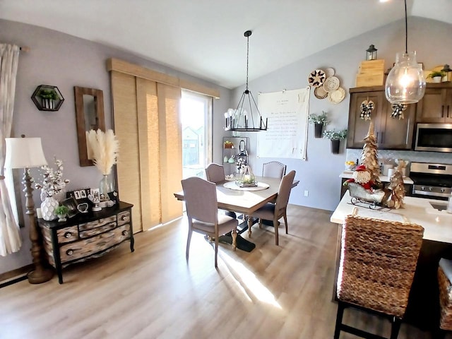 dining area featuring an inviting chandelier, vaulted ceiling, and hardwood / wood-style flooring