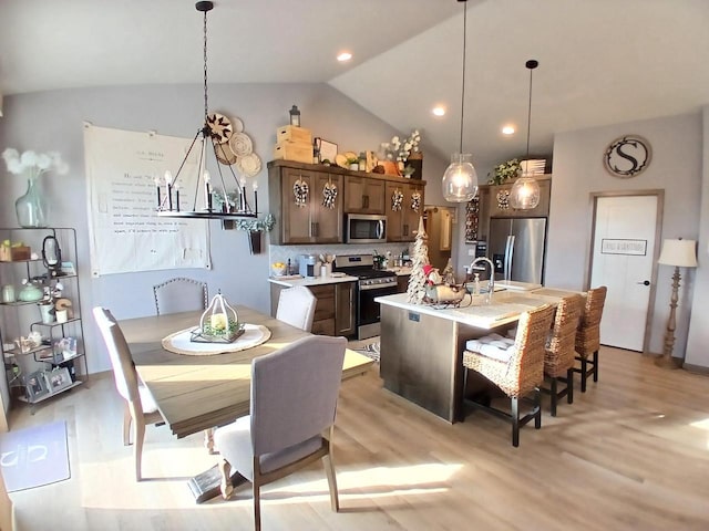 dining room featuring light hardwood / wood-style flooring, a chandelier, lofted ceiling, and sink