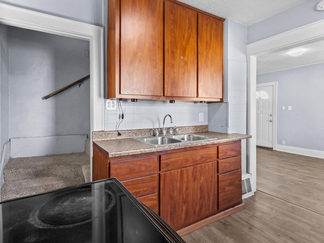 kitchen with sink, backsplash, stove, light hardwood / wood-style floors, and a textured ceiling