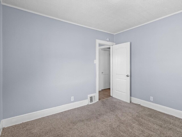 unfurnished room with crown molding, carpet floors, and a textured ceiling