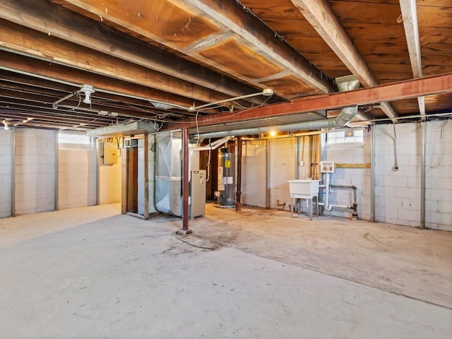 basement with heating unit, water heater, and sink