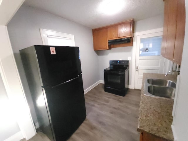 kitchen featuring light stone counters, sink, black appliances, and light wood-type flooring